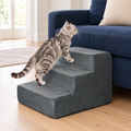 Tabby cat climbing PETMAKER grey three-step foam stairs beside a sofa