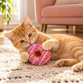 Ginger cat playing with pink strawberry donut catnip toy