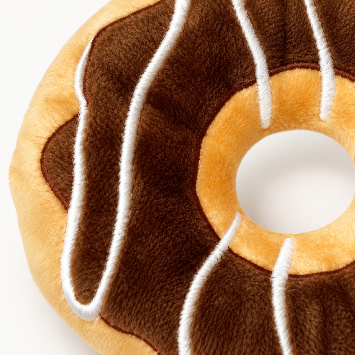 Close-up of the donut toy's brown plush fabric and white drizzle-style trim