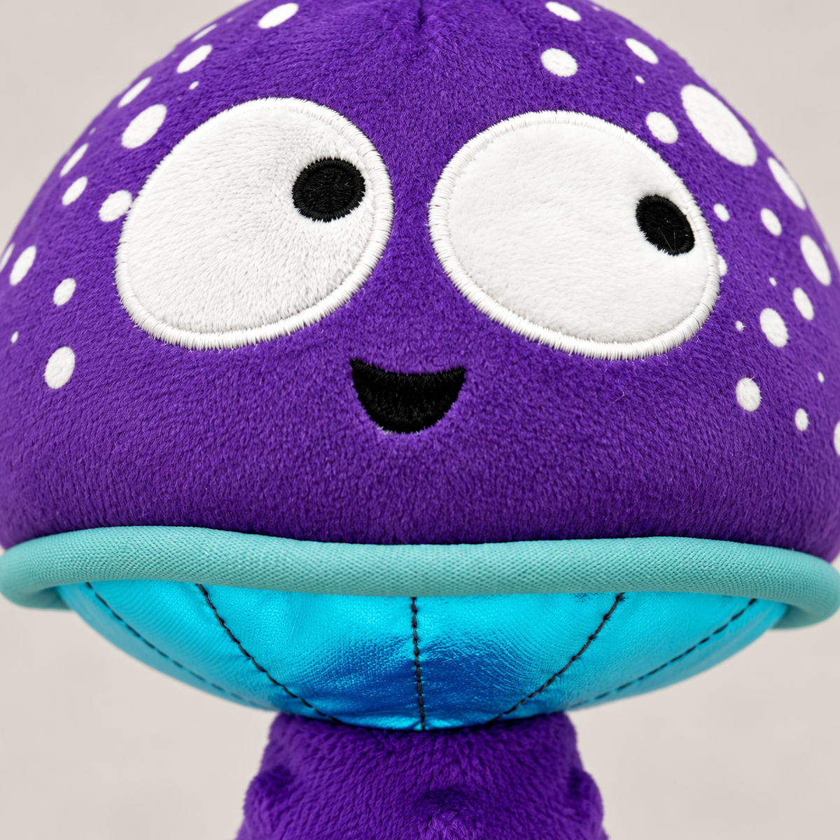 Close-up of the purple mushroom's embroidered face, mint trim and turquoise underside
