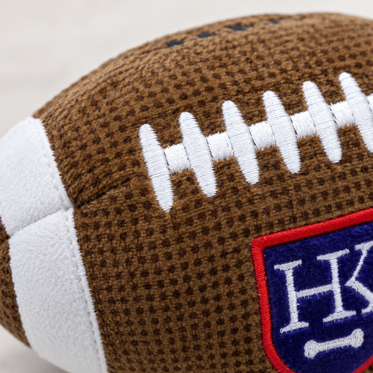 Close-up of the football's brown plush fabric and white embroidered laces