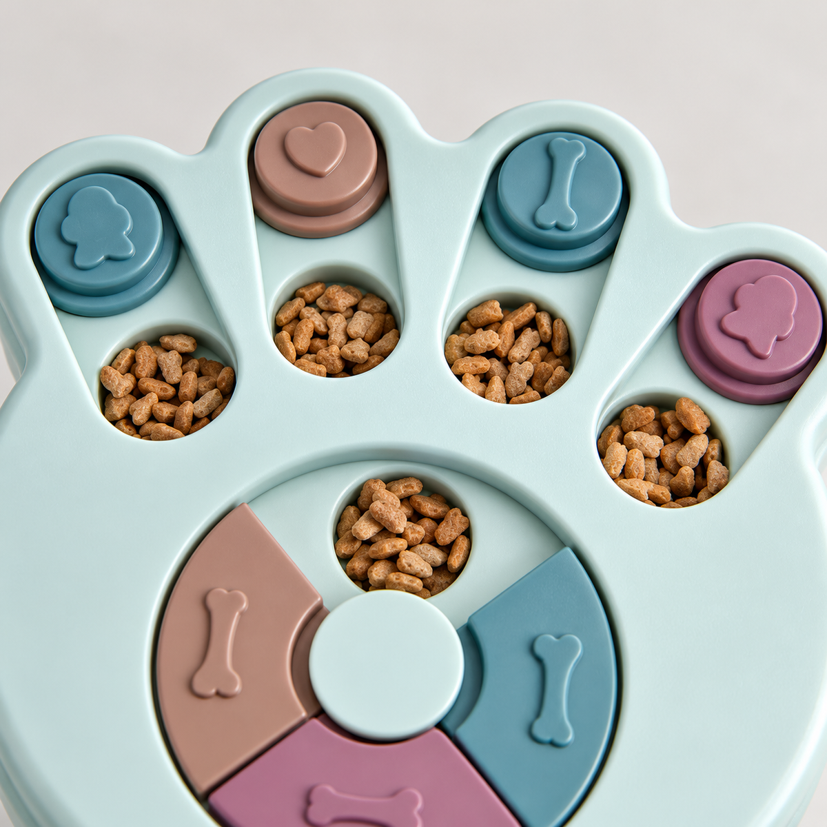 Close-up of the paw-shaped puzzle's sliding covers, rotating centre and food wells, shown with dry food