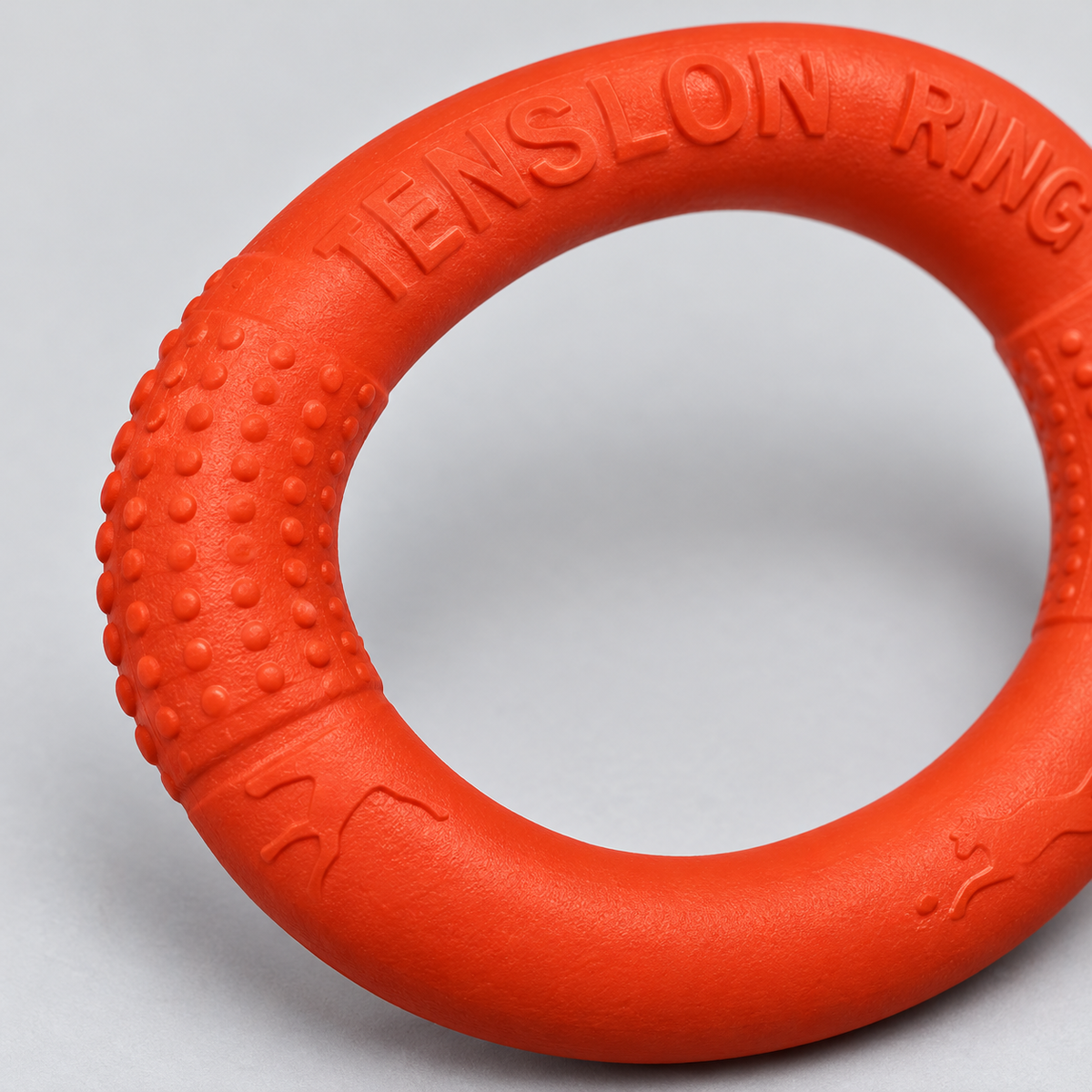 Close-up of the orange dog training ring's raised grip texture and rounded edge