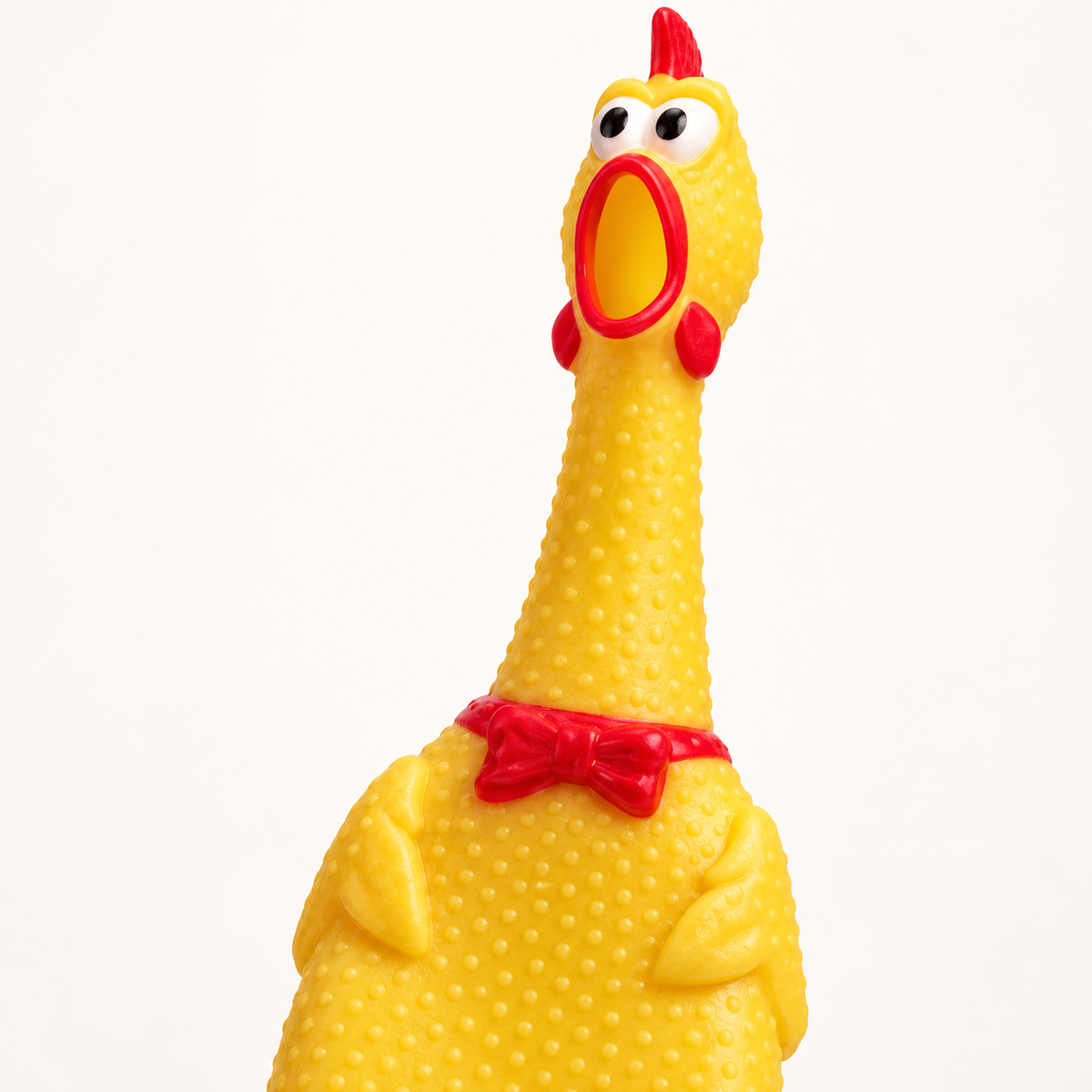 Close-up of the yellow squeaky chicken dog toy's textured rubber, red bow and cartoon face